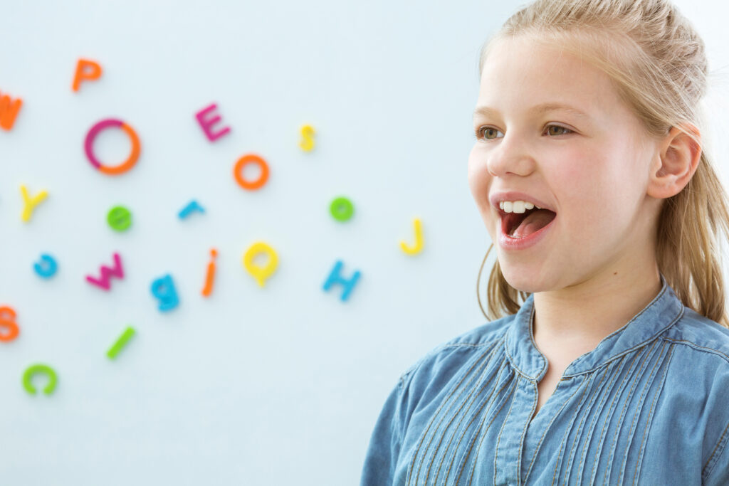 Girl speaking, with colorful magnet letters showing her communication visually